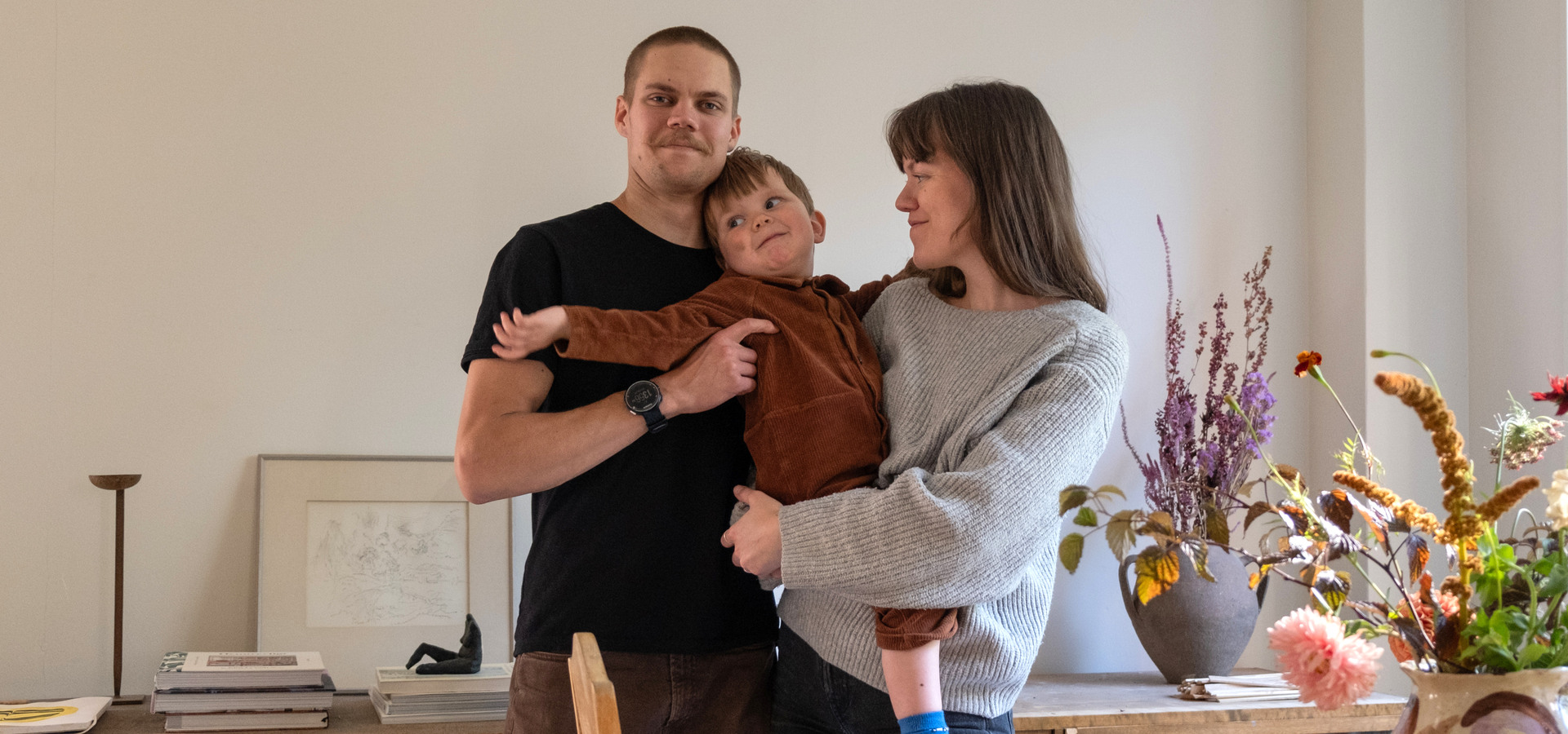 Pappa och mamma håller sitt barn inomhus.