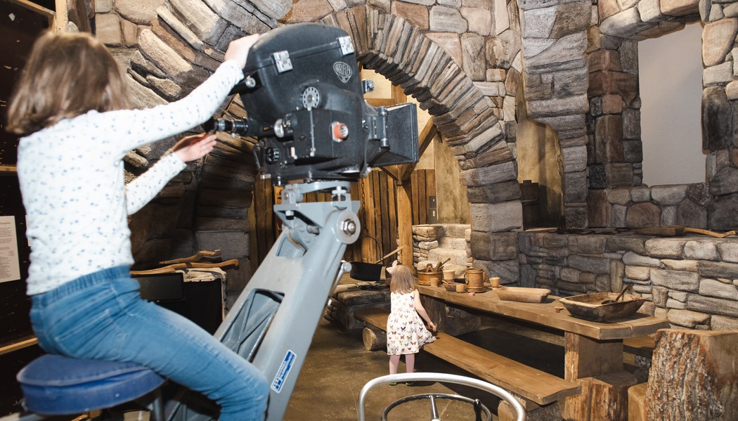 Två barn som leker med en filmkamera och föremål från ett filmset.