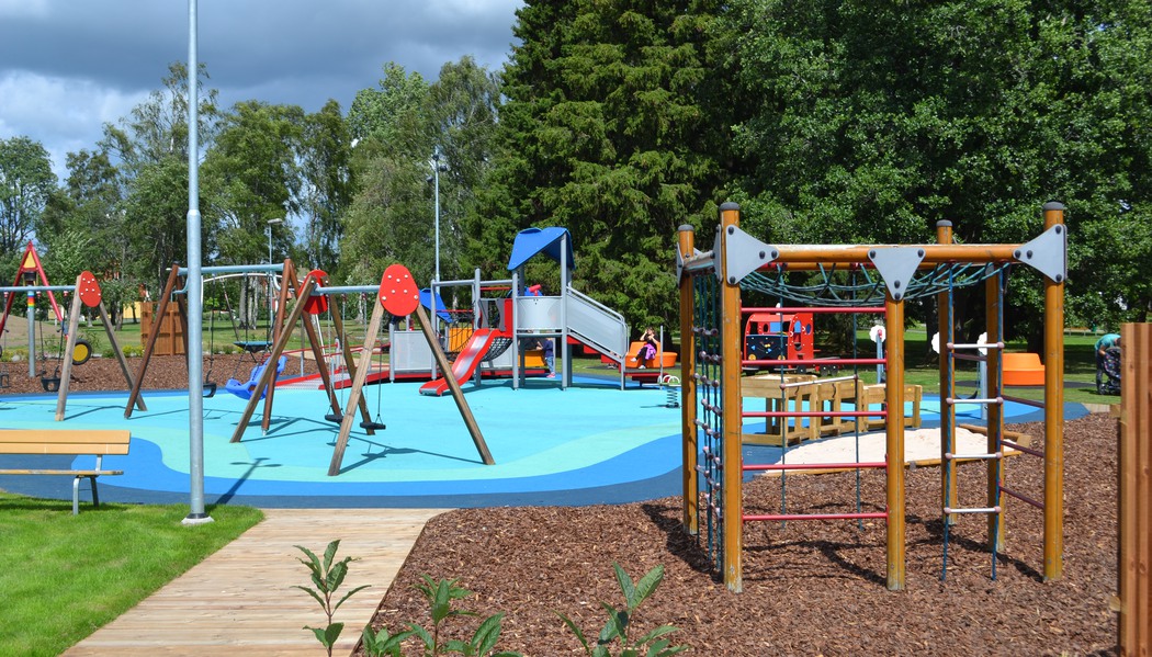 Lekpark med gungor, klätterställning och rutschkana.