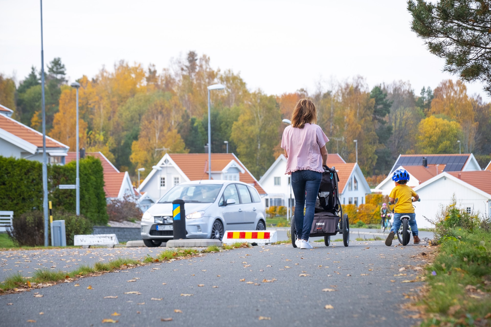 Mamma och barn som promenerar i villaområde.