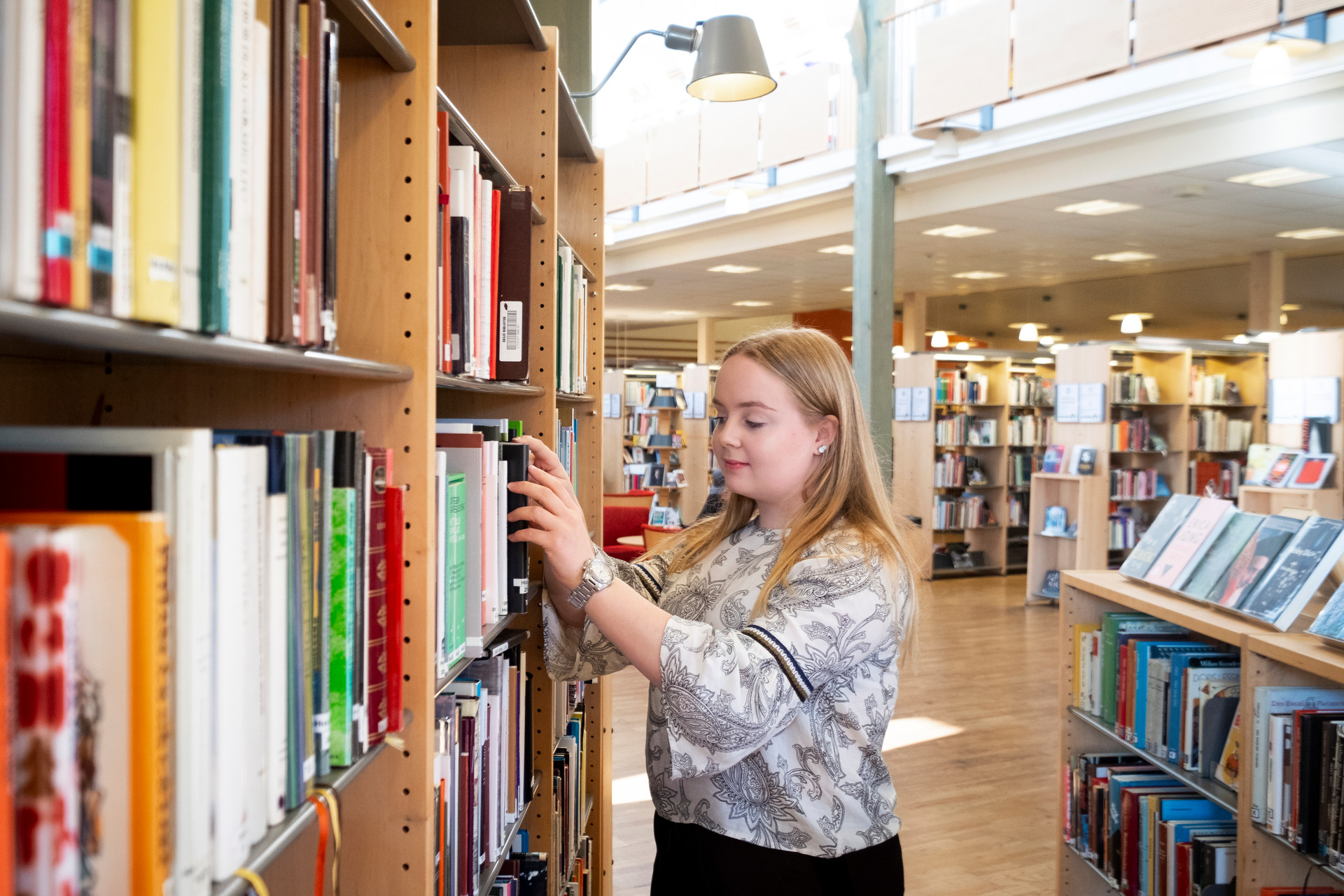Flicka som kollar på böcker i en bokhylla