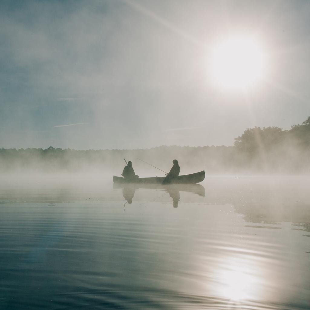 Fiskare i båt i morgondimma.