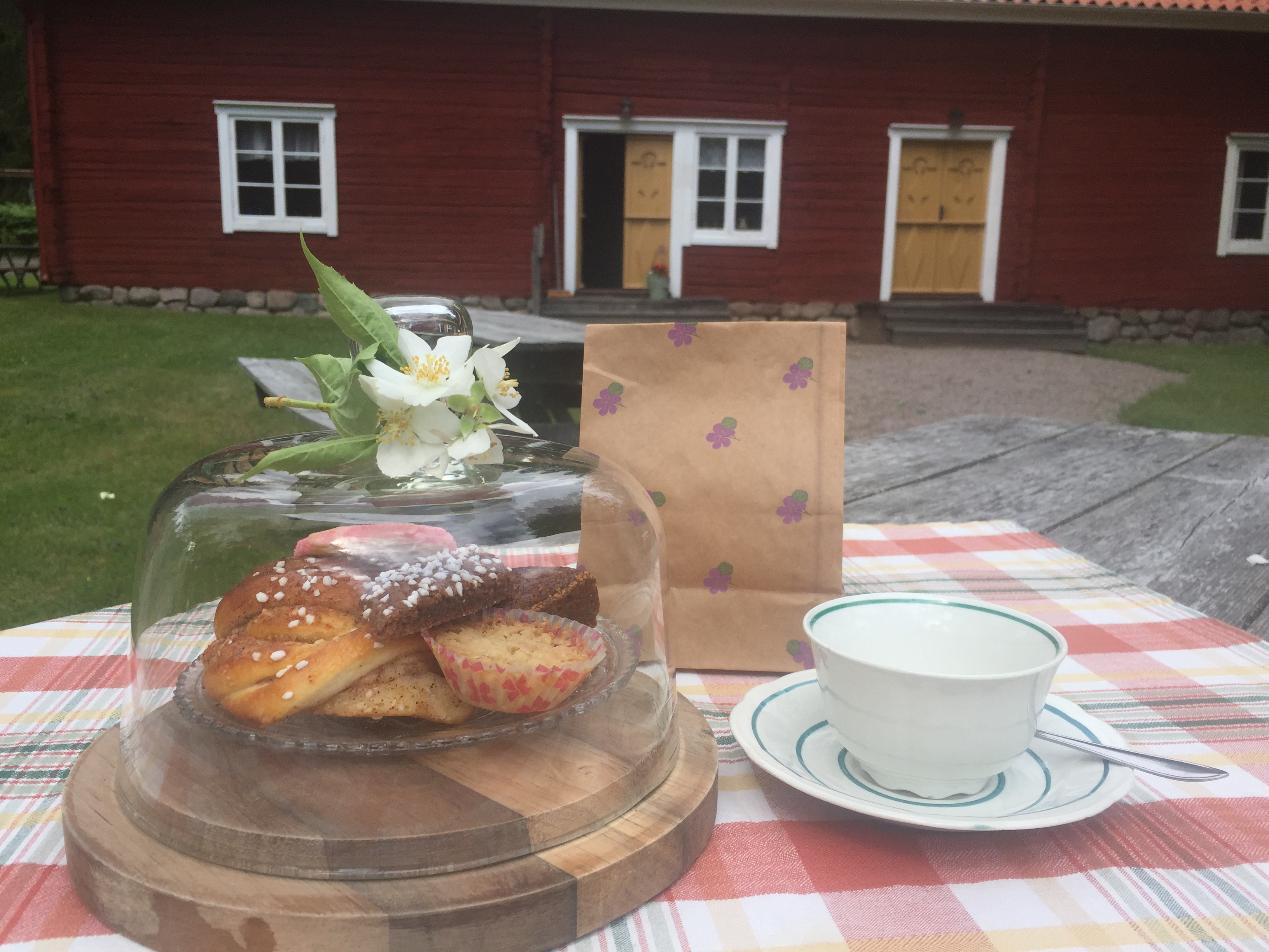 Fika och kaffekopp framför en småländsk lada