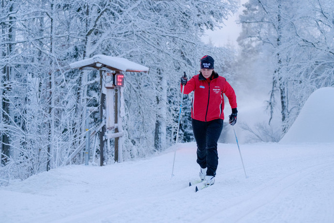Kvinna som åker längdskidor i konstsnöspår